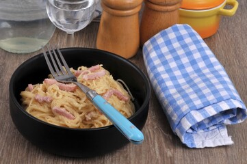 Spaghetti carbonara servis dans une assiette avec une fourchette en gros plan