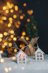 Garland in the form of wooden houses with yellow bulbs close-up on white-black background. Christmas, new year background