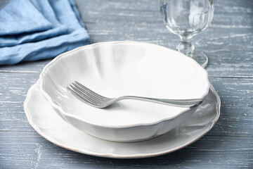 An empty plate with a fork on the table with an empty glass of wine and a napkin. Studio shot from...
