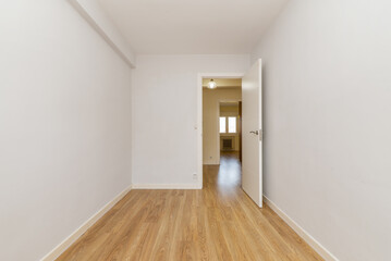 An empty room freshly painted plain white and with small floors of new driftwood flooring