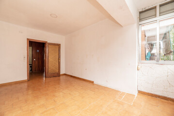 An old and used empty room with tiled floors and enclosed terrace addition