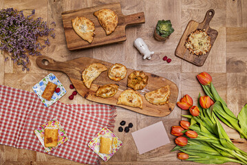 A still life with flowers and assorted vegan empanadas, vegan desserts and berries