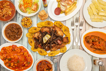 A still life of typical Caribbean recipes with roast beef and chicken with fried plantains, mofongo, white rice, fish with coconut sauce, fried yucca, salads and assorted stews