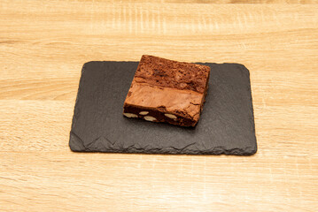 A delicious chocolate almond brownie dessert on a black slate plate