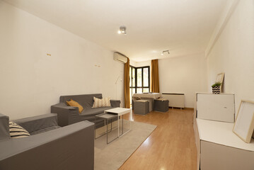 Living room of a house with gray fabric sofas, retractable coffee tables, a glass and aluminum gazebo in the corner