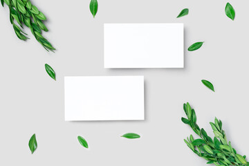 Mockup one cutaway, discount, business card on a grey minimalism background and green leaves branch with copy space. Template for design