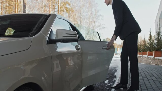 Businessman getting into the backseat of his personal car after driver opening door for him