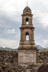 Fototapeta na wymiar A church buried by lava of the Paricutín volcano in Parangaricutirimucuaro, Michoacan, Mexico. The ruins of an old church. Bell tower. 