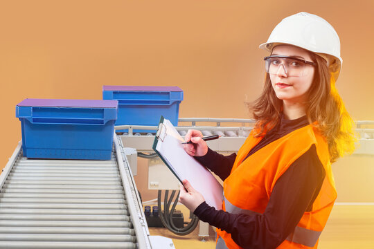 Woman inspects work of conveyor. Factory employee near production line. Blue plastic crates are on conveyor belt. Factory employee with clipboard. Woman looking at camera while standing near conveyor