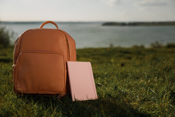 A school bag and a notebook on the grass near the sea