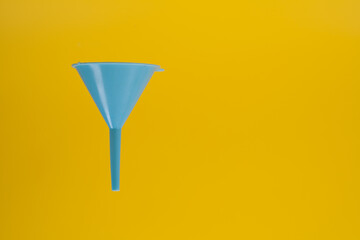 close up landscape orientation of blue plastic  kitchen funnel isloated on a yellow background
