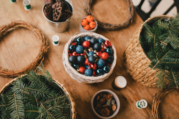 Items for making Christmas wreath: pine branches, cones and holiday decorations on wooden table.