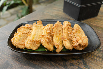 A plate of Indonesian pisang goreng tepung or fried banana snack for breakfast or hang out. Usually served with hot tea or coffee