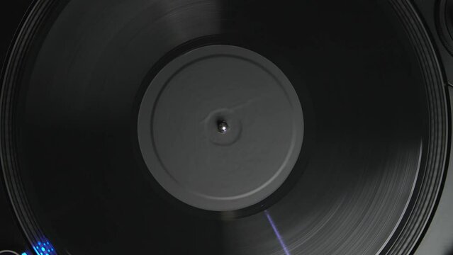 Turntable plays vinyl record disc with music. Analog audio equipment for disc jockey filmed directyl from above in 4k