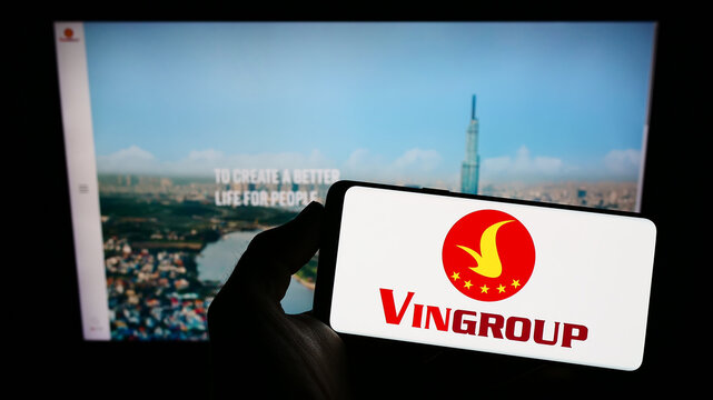 Stuttgart, Germany - 12-01-2022: Person holding smartphone with logo of Vietnamese conglomerate Vingroup JSC on screen in front of website. Focus on phone display.