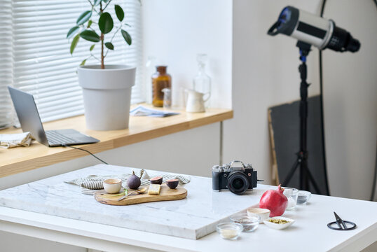 Horizontal image of photo studio with table preparing for taking pictures of still life with professional camera