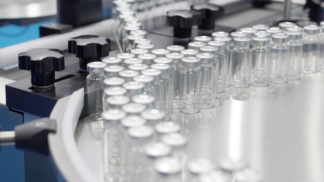 The movement of empty vials on a conveyor belt.