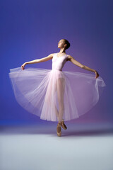 Fototapeta premium Ballet dancer. Young and incredibly beautiful ballerina is posing in point shoes and dancing. Isolated in lilac neon background. Beauty of a classical ballet art.