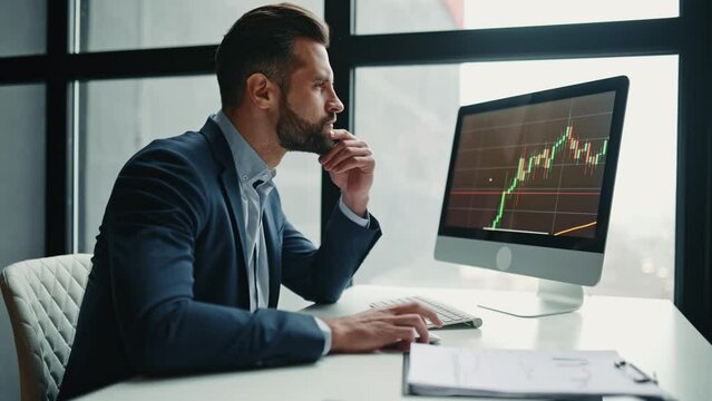 Busy focused pensive smart successful caucasian male stock investor, broker, financial expert, sit at work desk, uses computer and charts, analyzes risks and prospects, rise or fall of cryptocurrency 