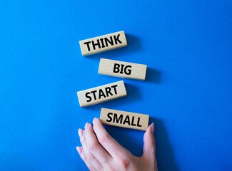 Think big start small symbol. Concept words Think big start small on wooden blocks. Beautiful blue background. Businessman hand. Business and Think big start small concept. Copy space