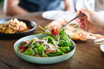 Eating salad. people eating Italian food Pasta, Pizza, Salad on the table.