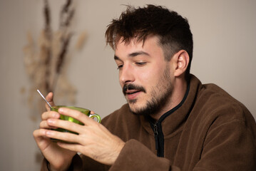 young boy drinking in green glass mug, wooden table rustic design decoration