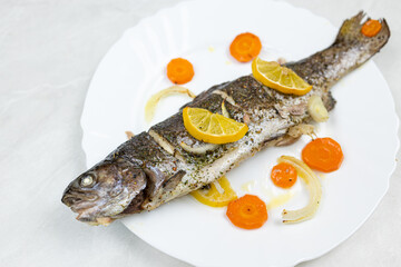 Baked trout served on the plate with vegetables