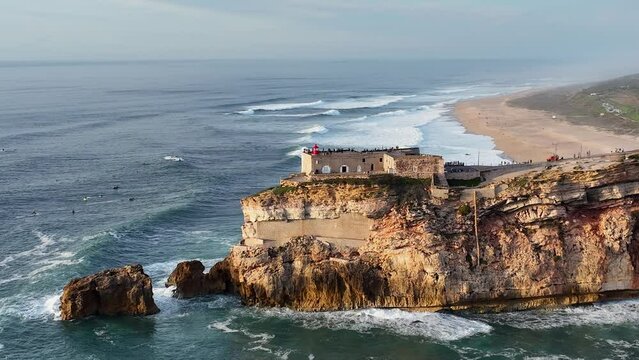 Lighthouse in Nazare, Portugal. Famous place for waves and surfing. Beach and Ocean Waves in Background. 4k