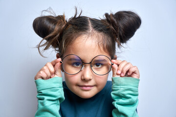 Caucasian little girl wearing glasses squinting while looking at camera isolated on white...