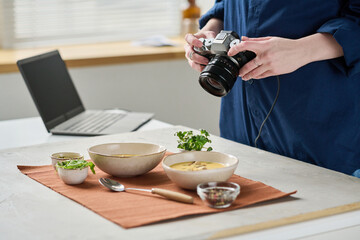 Close-up of photographer making close-up portrait of soup in bowls with digital camera