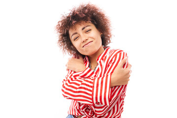 Young curly brunette woman hugging herself and smiling isolated on white studio background. Self love and self care concept.