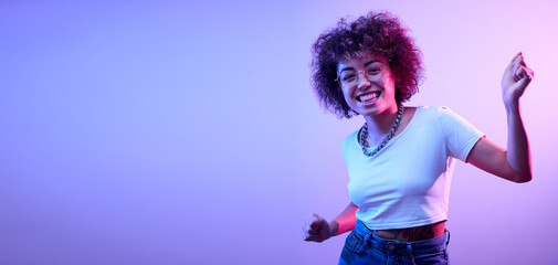 Portrait of cool kazakh girl with curls and tattoo dancing and posing in neon light isolated on studio background
