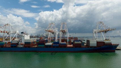 Fototapeta premium commercial port loading and unloading cargo from container ship import and export by crane for distributing goods by trailers transported to customers and dealers