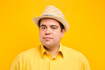 Portrait of positive fat man in hat kindly smiling isolated on yellow studio background, travel vacation concept