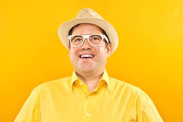 Portrait of positive fat man in hat kindly smiling isolated on yellow studio background, travel vacation concept