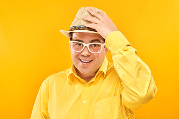 Portrait of positive fat man in hat kindly smiling isolated on yellow studio background, travel...