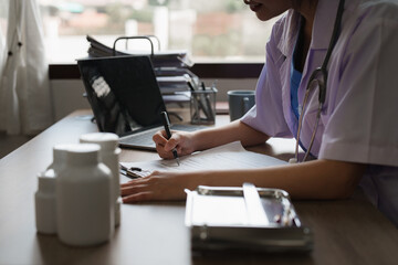 Portrait of female Asian doctor working with patient document in her office at clinic