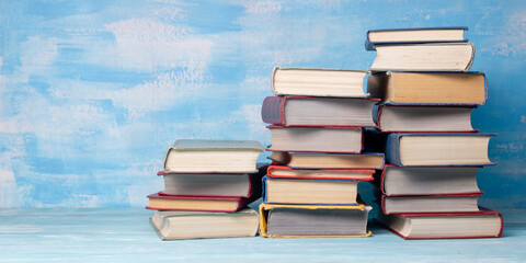 Composition with vintage old hardback books, diary, fanned pages on wooden deck table and red background. Books stacking. Back to school. Copy Space. Education background.	