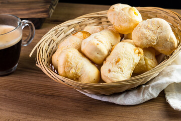 Brazilian Pão de queijo, fresh cheese breads on rustic wood and a hot cup of coffee. Selective focus