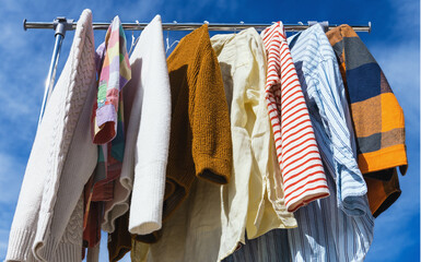  Low angle view at colourful clothes hanging on rail against blue sky.