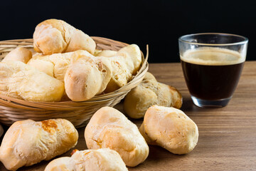 Brazilian Pão de queijo, fresh cheese breads on rustic wood and a hot cup of coffee. Selective focus