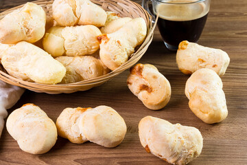 Brazilian Pão de queijo, fresh cheese breads on rustic wood and a hot cup of coffee. Selective focus