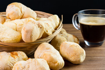 Brazilian Pão de queijo, fresh cheese breads on rustic wood and a hot cup of coffee. Selective focus
