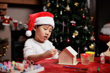 Obraz na płótnie Canvas young girl wearing santa hat was making Christmas craft at home