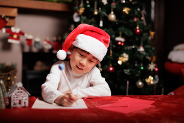young girl wearing santa hat was writing  letter to Santa at home