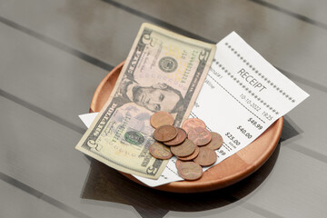 Tips and receipt on wooden table, closeup