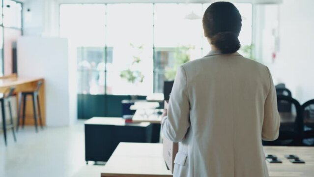New job. Excited successful motivated mixed race woman, walks into new working office, holding a cardboard box with work attributes in her hands, inspects the workspace in amazement, smiling happily