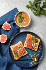 Tasty toasts served with fig, peanut butter and walnuts on light grey marble table, flat lay