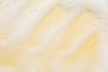 White washing foam on yellow background, top view