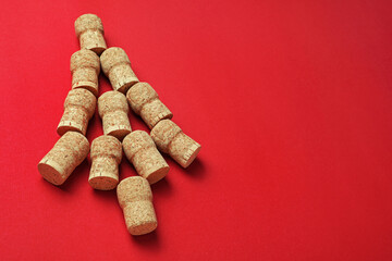 Fototapeta na wymiar Christmas tree made of wine corks on red background. Space for text